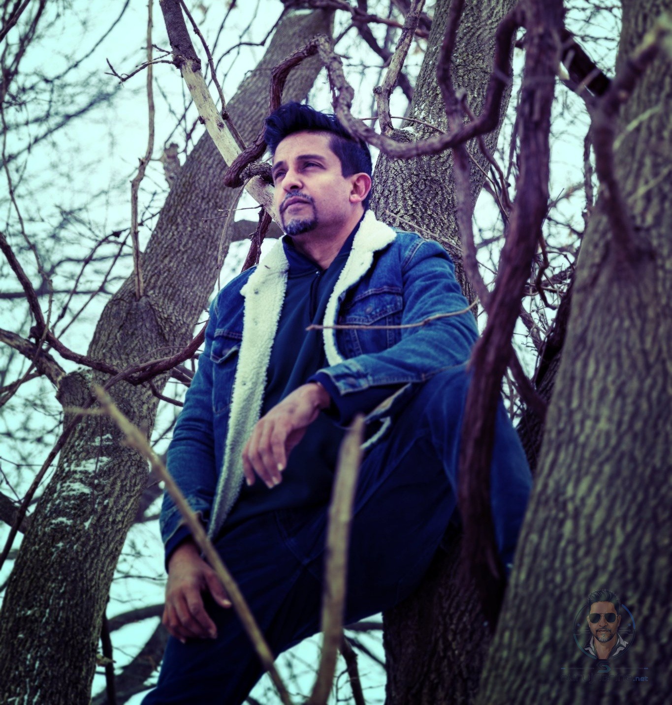 Andy leaning against a tree, looking upward and away, in quiet thought
