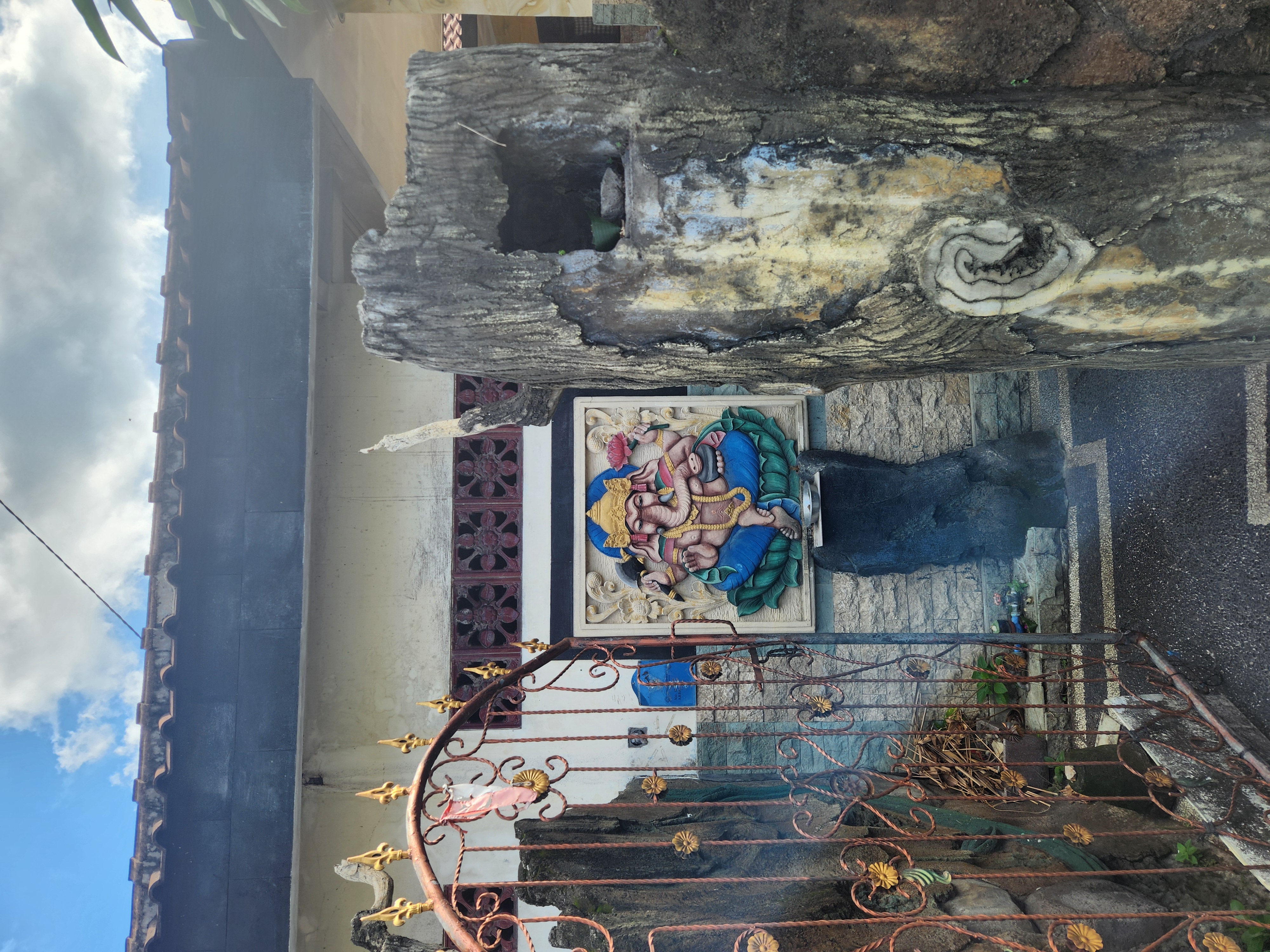 Colorful Ganesha relief on a wall beside an ornate gate in Bali, incense smoke below